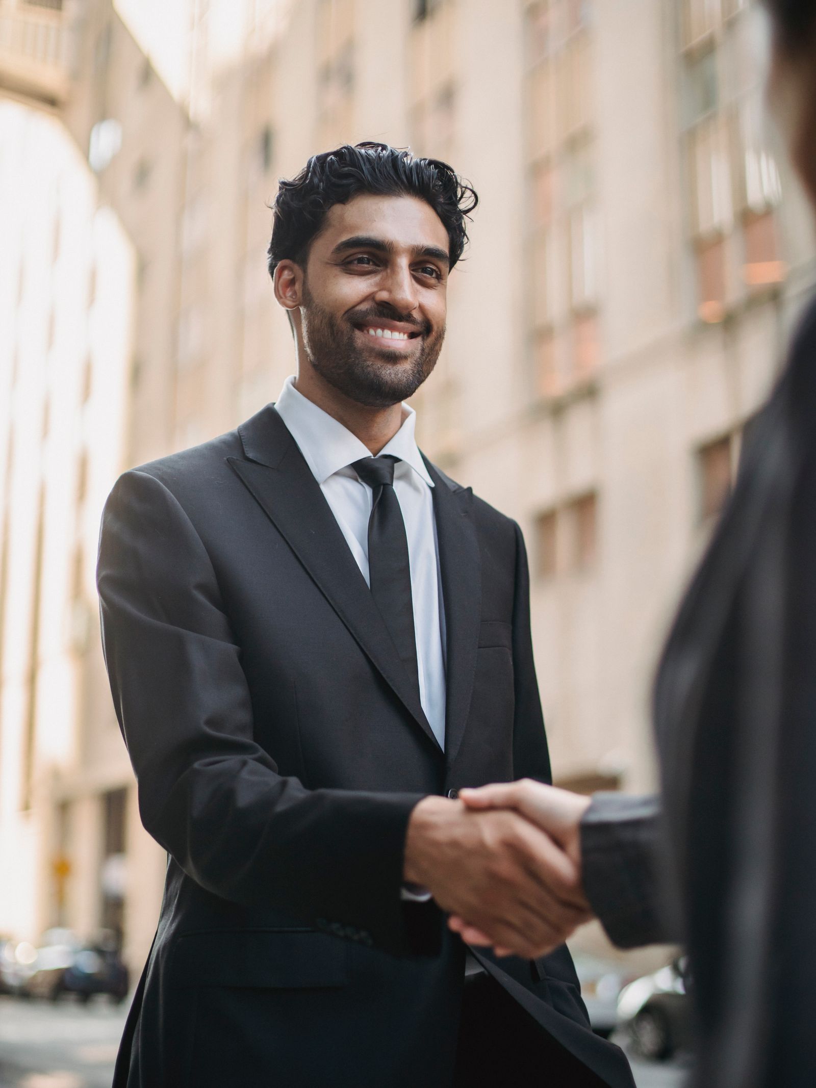 A confident Indian business professional shaking hands on a clear, fair agreement